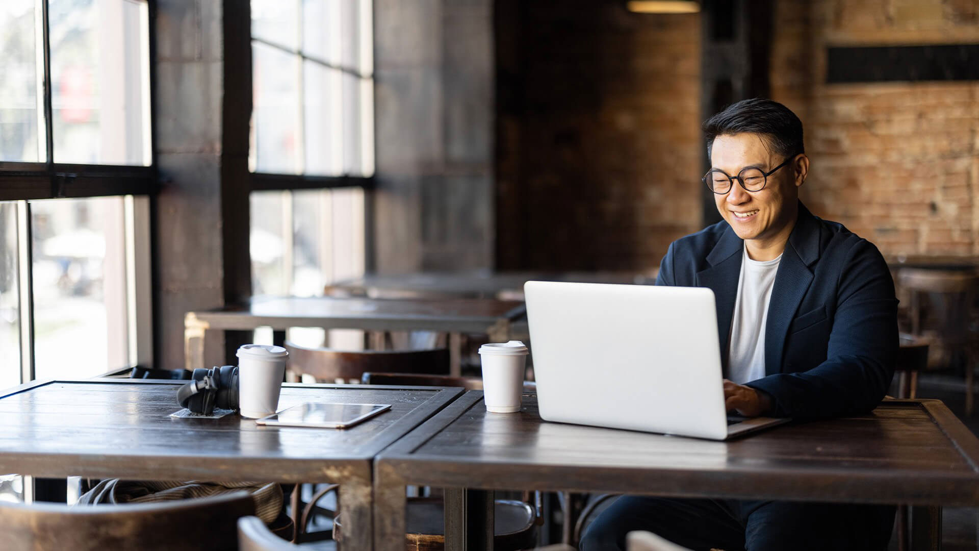 A man working on his laptop at a cafe table.