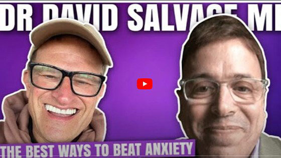 The image features two men, one on the left with glasses, wearing a hat, and smiling, and another on the right with a beard, wearing glasses and a blue shirt, also smiling. They are both looking towards the camera. Between them, there s text that reads  DR DAVID SALVAGE ME  and below it, additional text states  THE BEST WAYS TO BEAT ANXIETY.  The style of the image appears to be a thumbnail for a video or an advertisement.